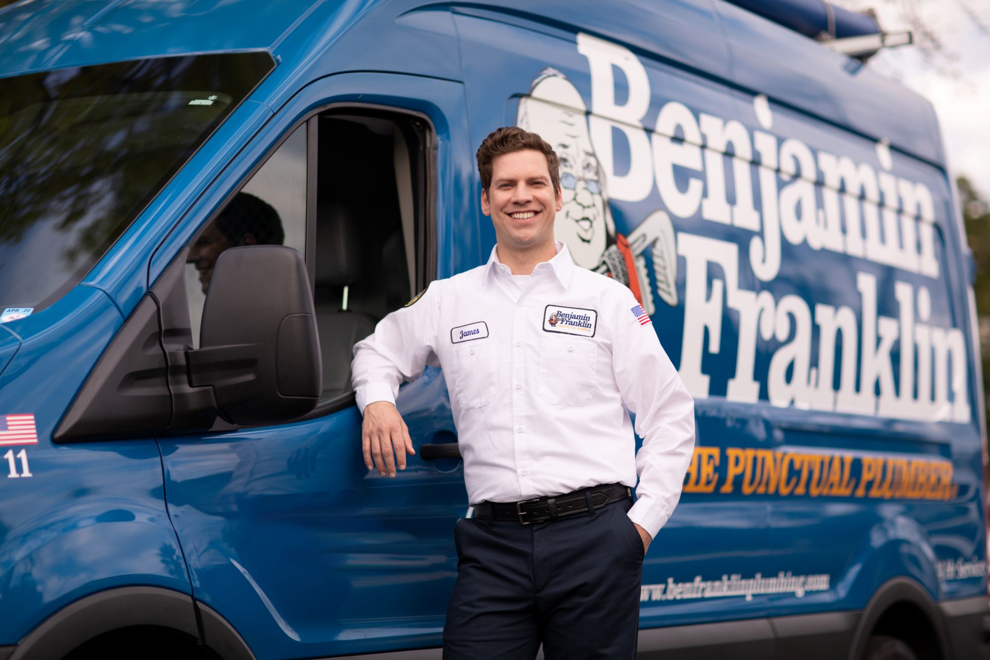 Benjamin Franklin Plumbing franchise owner in front of a branded truck.